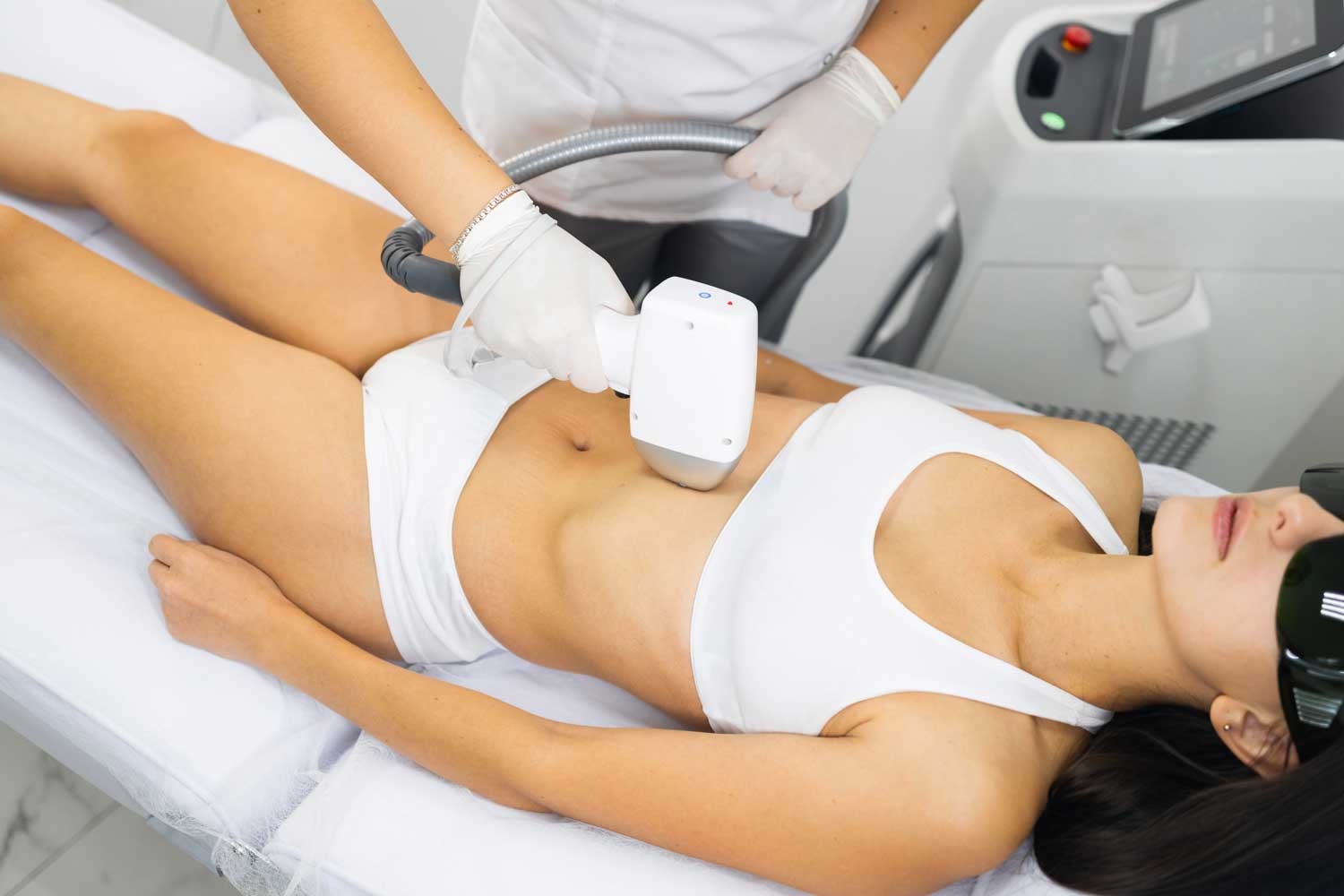 Woman receiving laser hair removal treatment on her stomach at a medical spa.